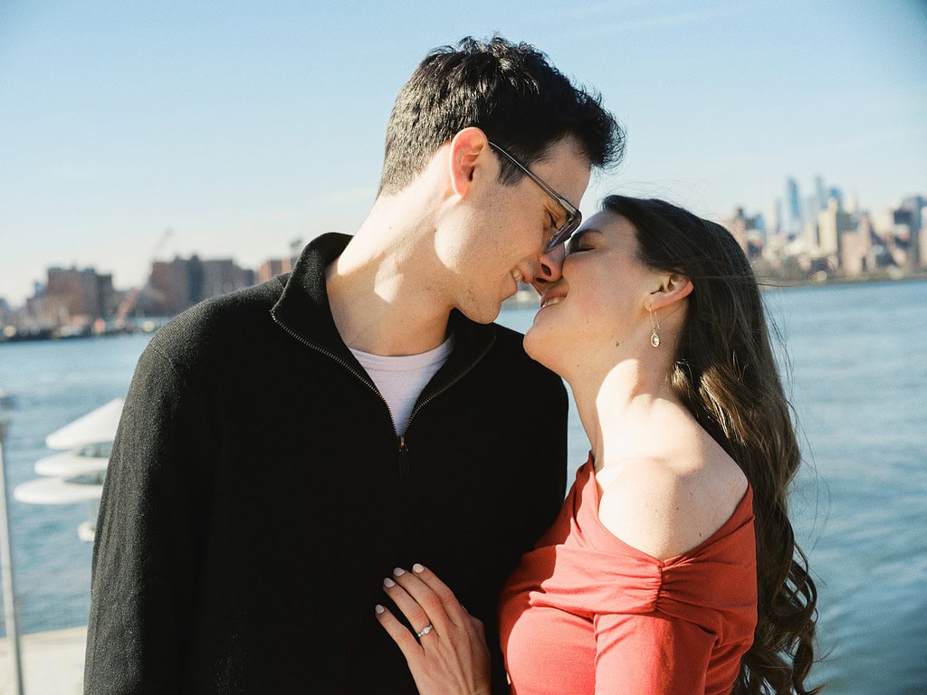 a man and woman kissing in front of the manhattan skyline