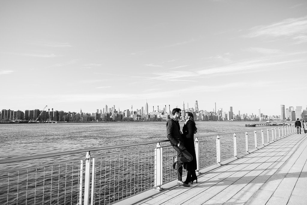 a man and woman standing on a bridge by water in Brooklyn