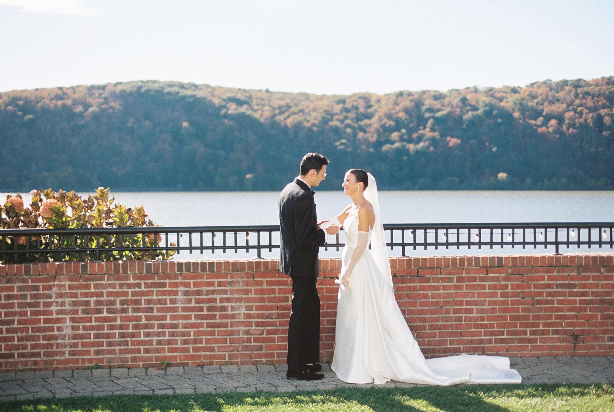 Wide portrait of Elizabeth and Matt at The Grandview riverside terrace with fall foliage hills and Hudson River — film wedding photography