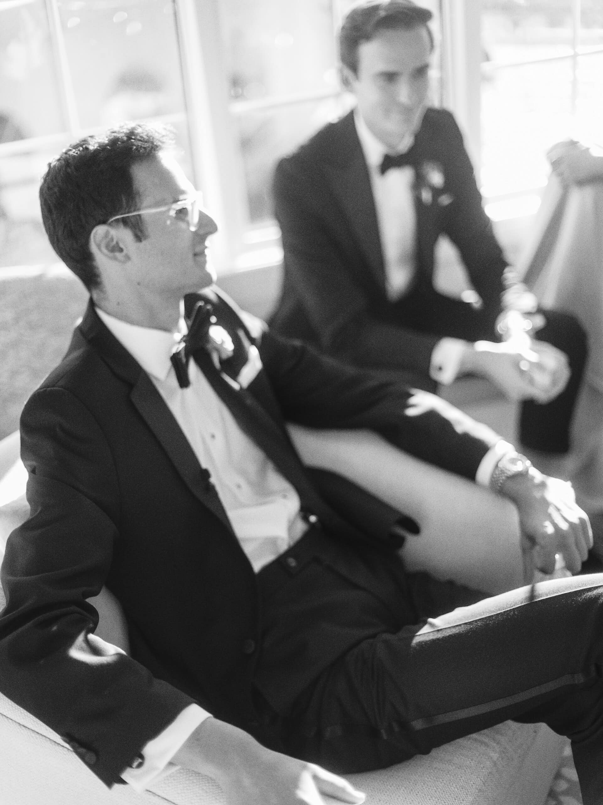 Black and white candid of groom Matt and groomsman relaxing before the ceremony at The Grandview — documentary wedding photography