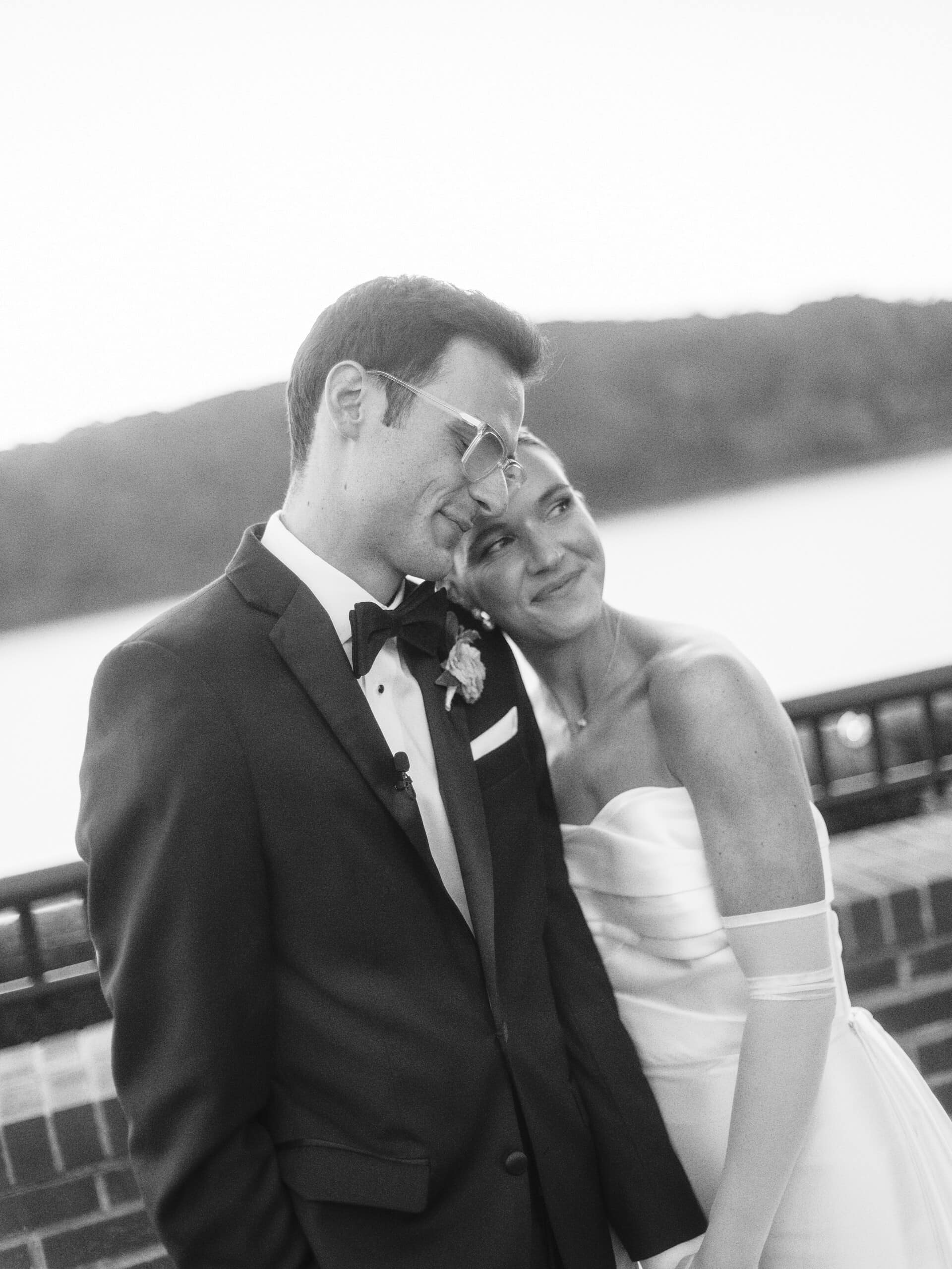 Black and white portrait of Elizabeth leaning her head on Matt's shoulder at The Grandview terrace with Hudson River behind them — post-ceremony wedding portrait